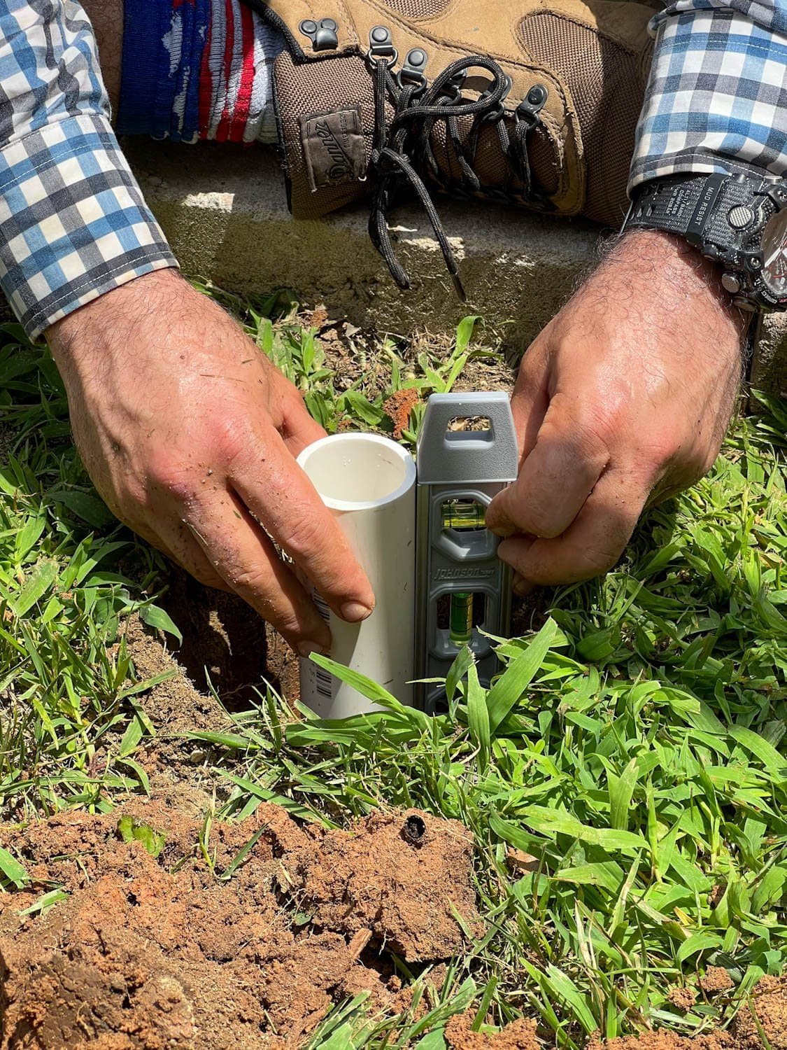 checking to make sure PVC pipe is level in 2 foot deep hole