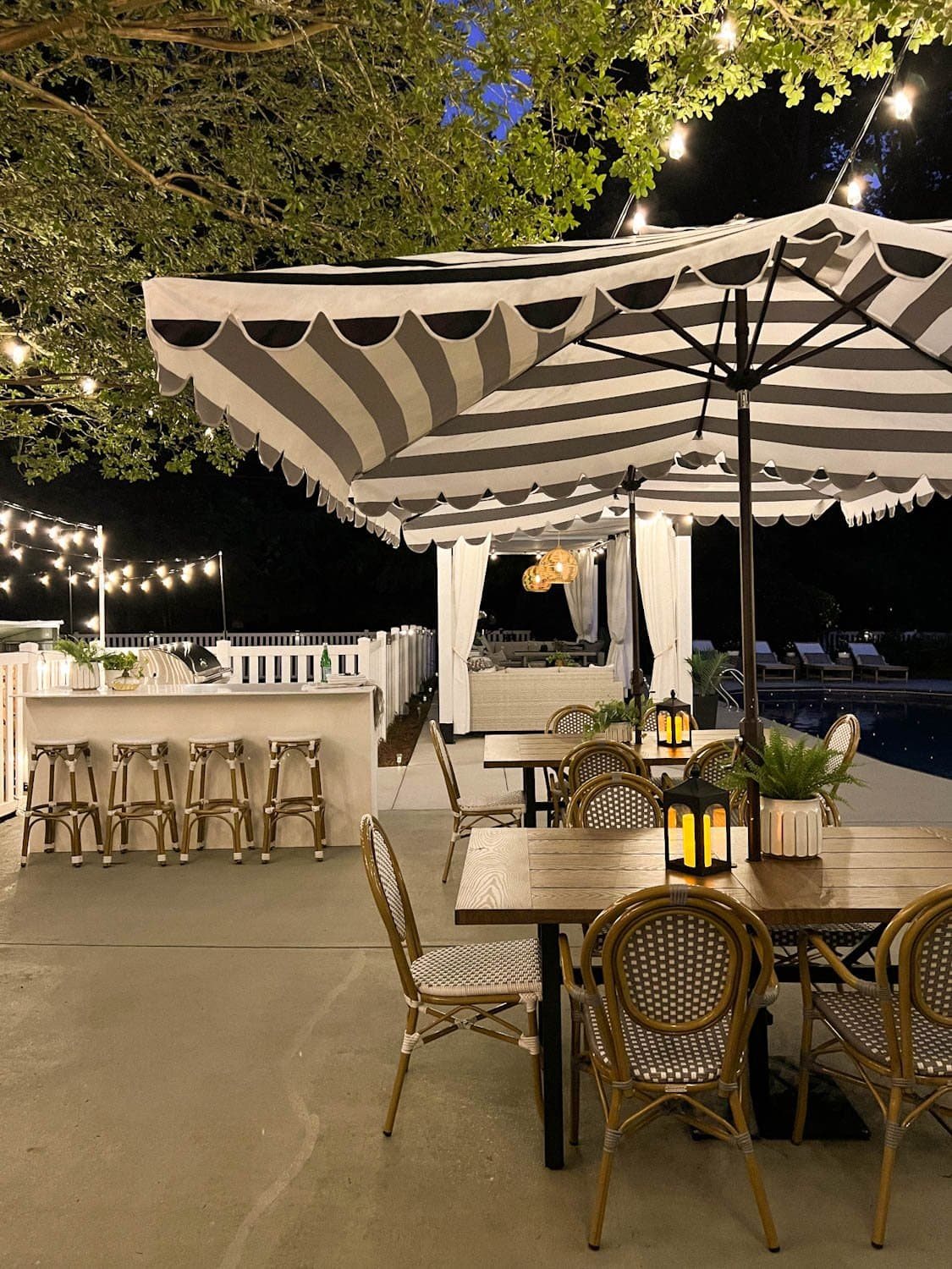 outdoor dining tables and outdoor kitchen with string lights overhead