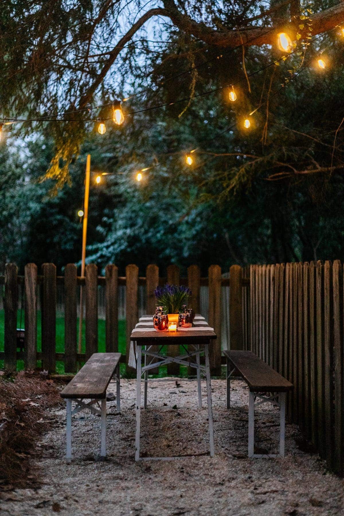 solar lights hanging from a tree above an outdoor table