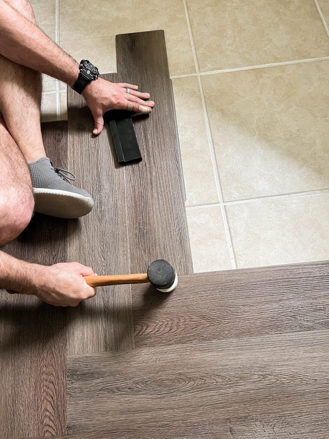 installing herringbone LVP floating floor over tile with mallet on seams to click into place
