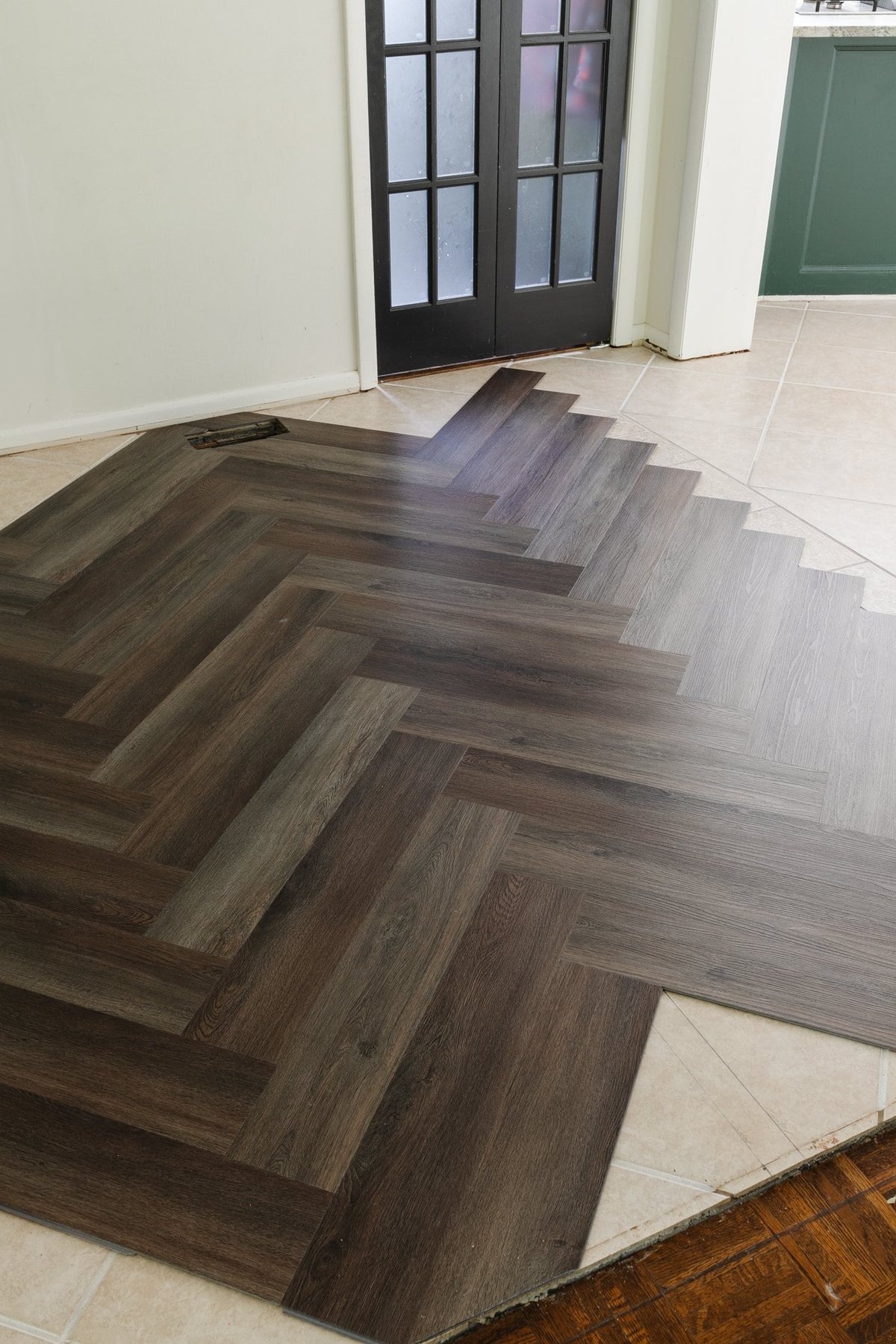 brown herringbone LVP floating floor over tile in a kitchen