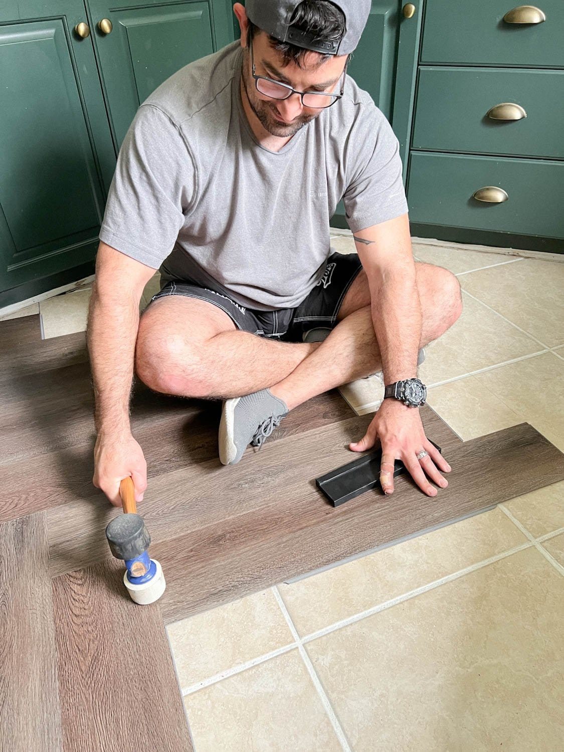 using a mallet to click LVP flooring into place during installation