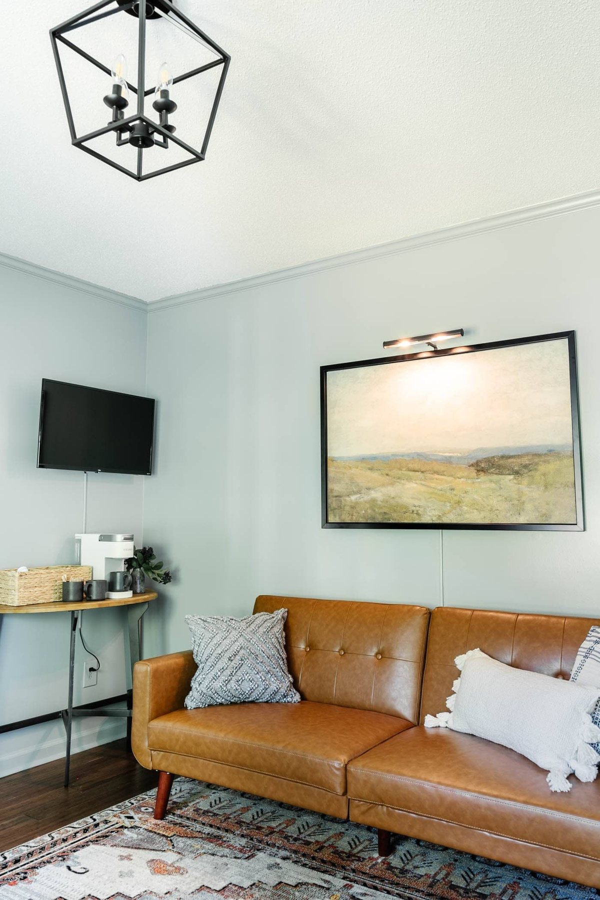 art with picture light above a home office lounge sofa with coffee bar table and TV