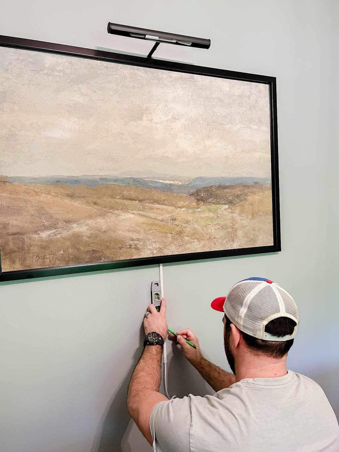 installing a picture light above a piece of art and wrapping cord in cord covers