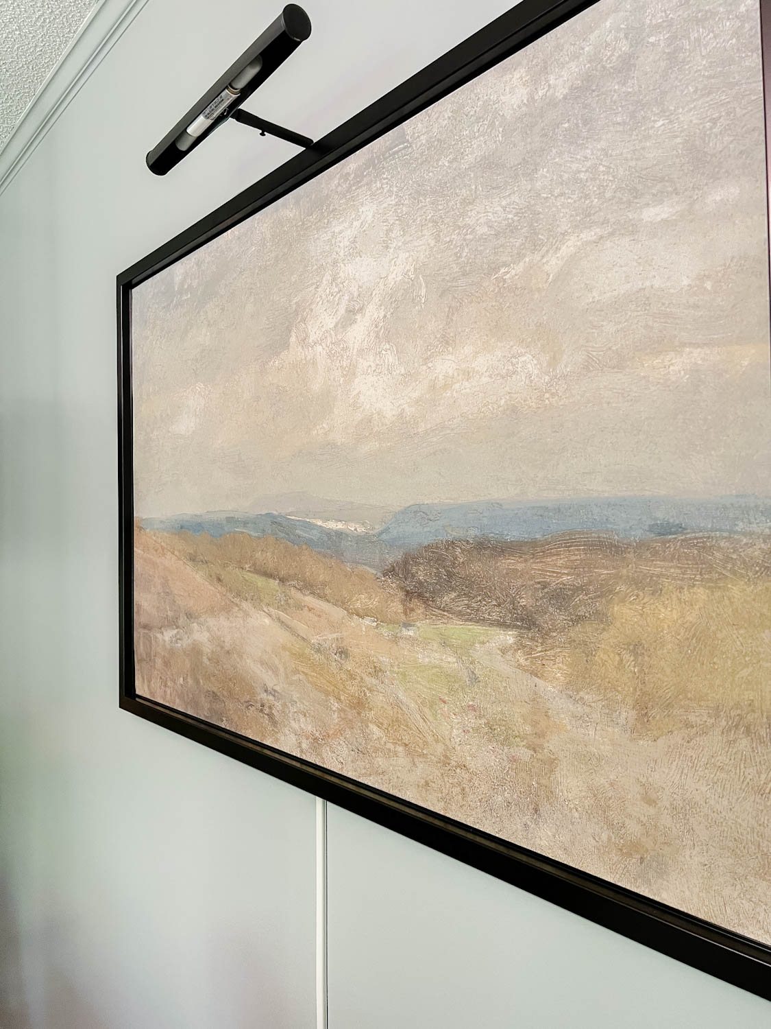 art light above art with cord stuck to wall below