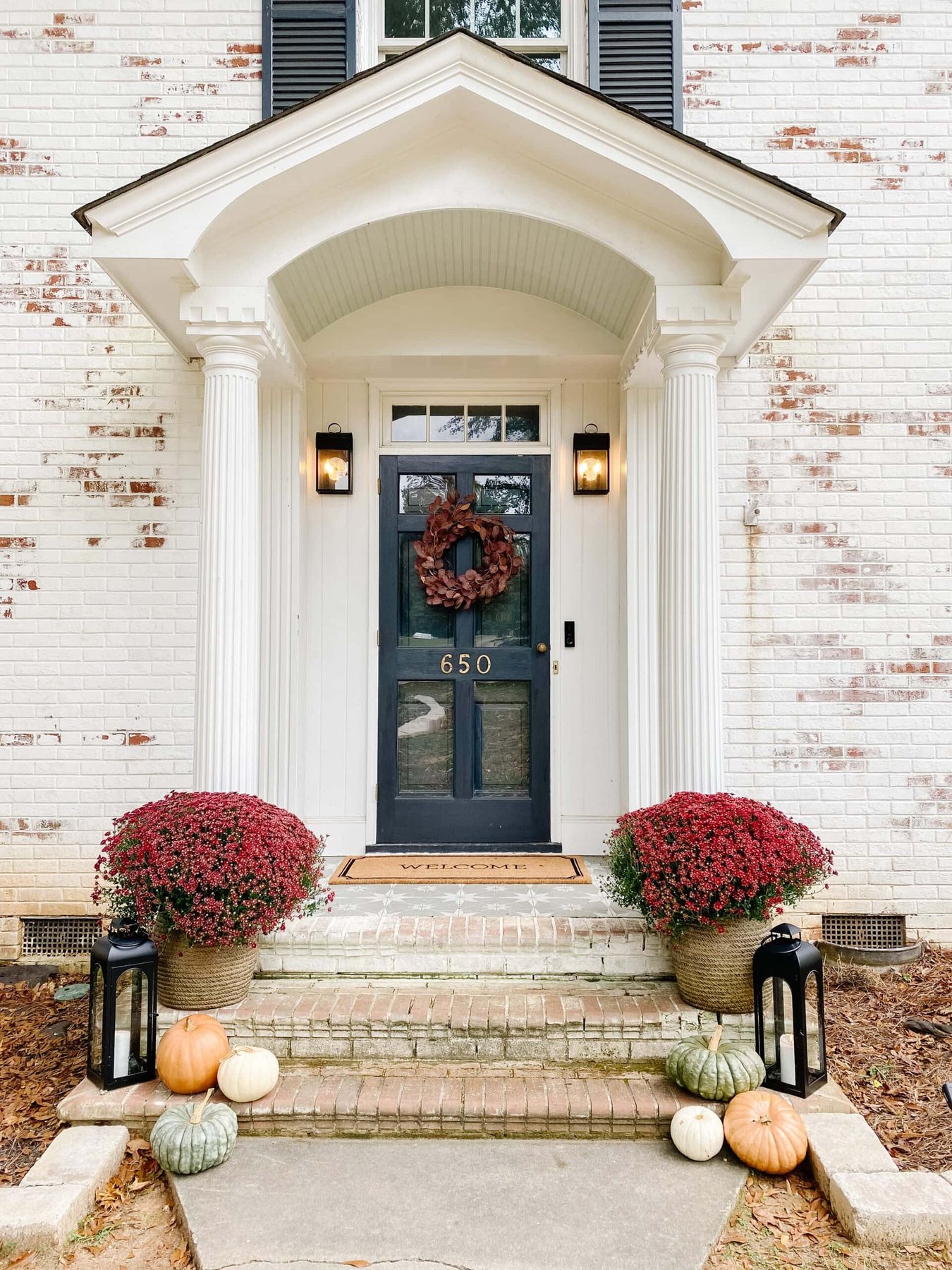 fall front porch with preserved pumpkins, lanterns, and mums