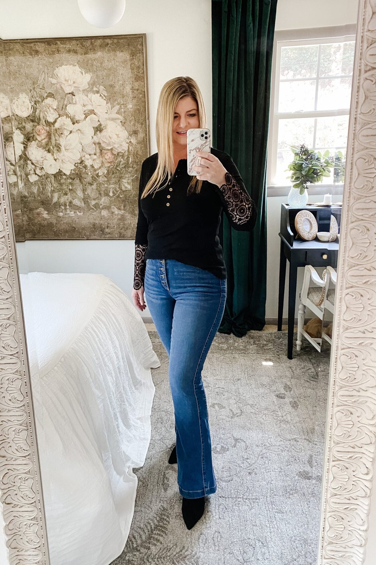 Slimming fall outfit idea: dark front tucked top, flare jeans, pointed toe boots