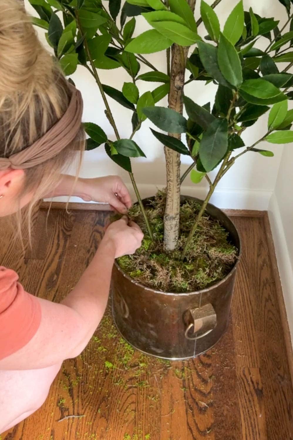 adding moss to a planter at the base of a faux tree