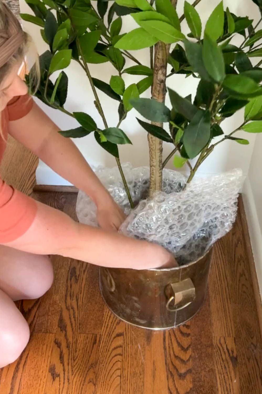 stuffing a thrifted brass planter at the base of an artificial tree