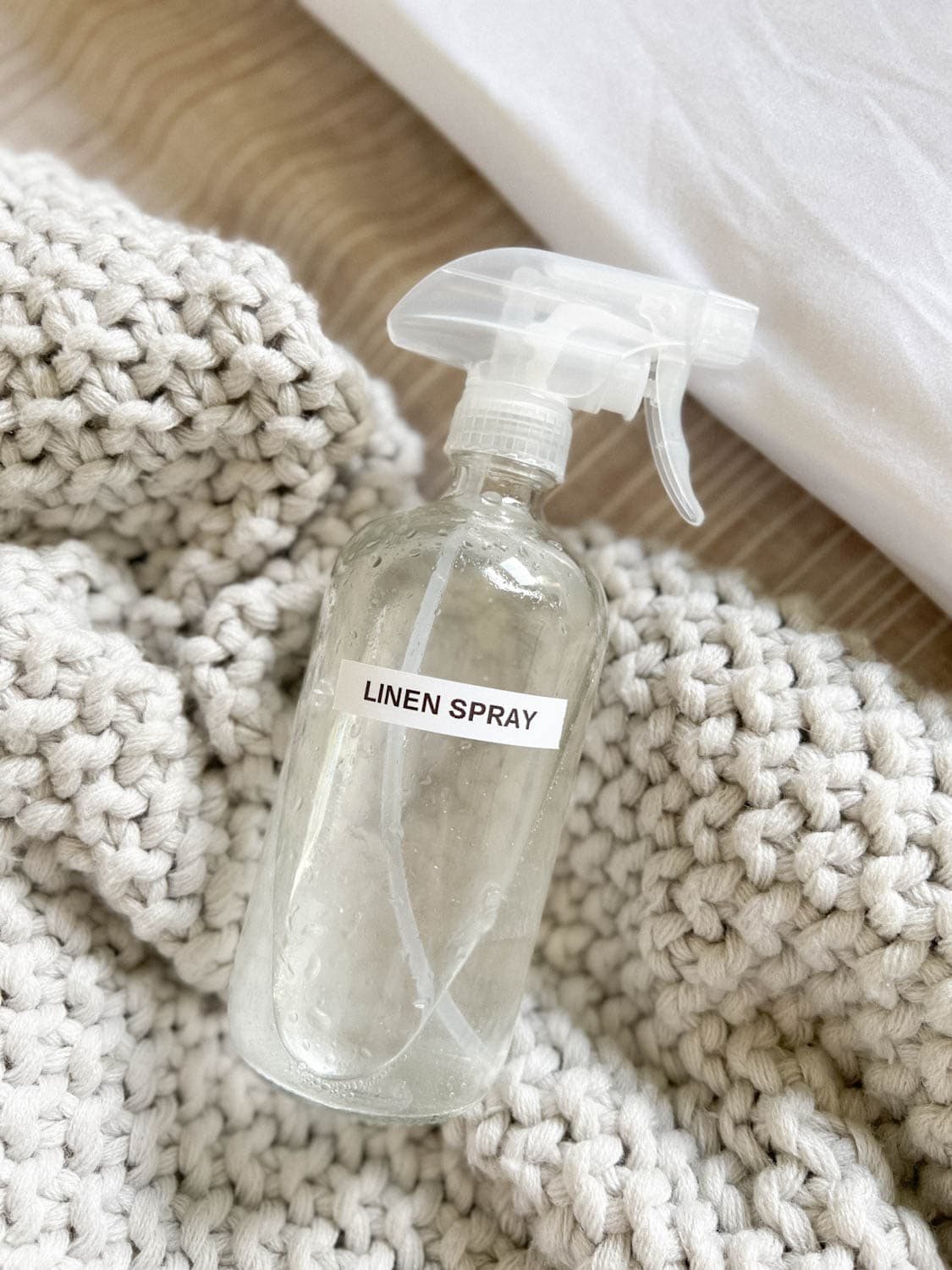DIY linen spray in a glass spray bottle on bedding