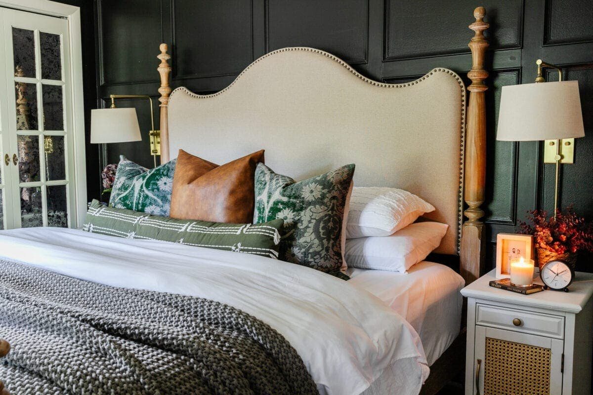 throw pillows on a bed with black walls and linen headboard