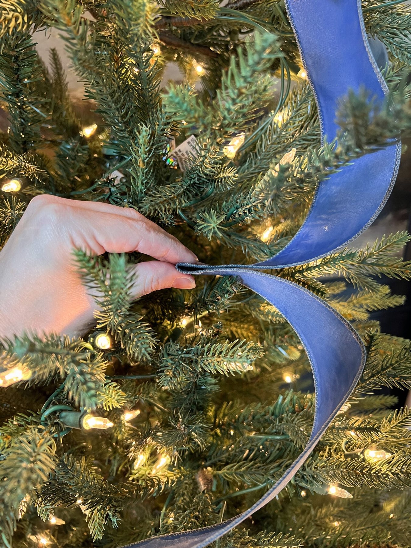 pinching middle of ribbon to tuck between branches