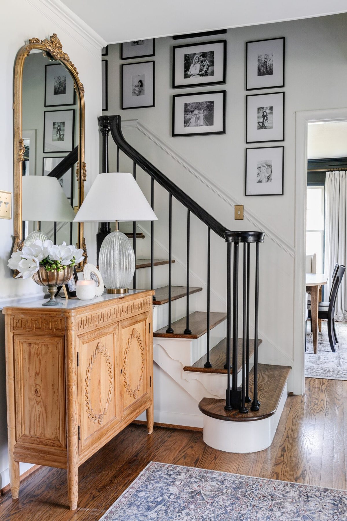 foyer with small staircase with black stair railing and family gallery wall