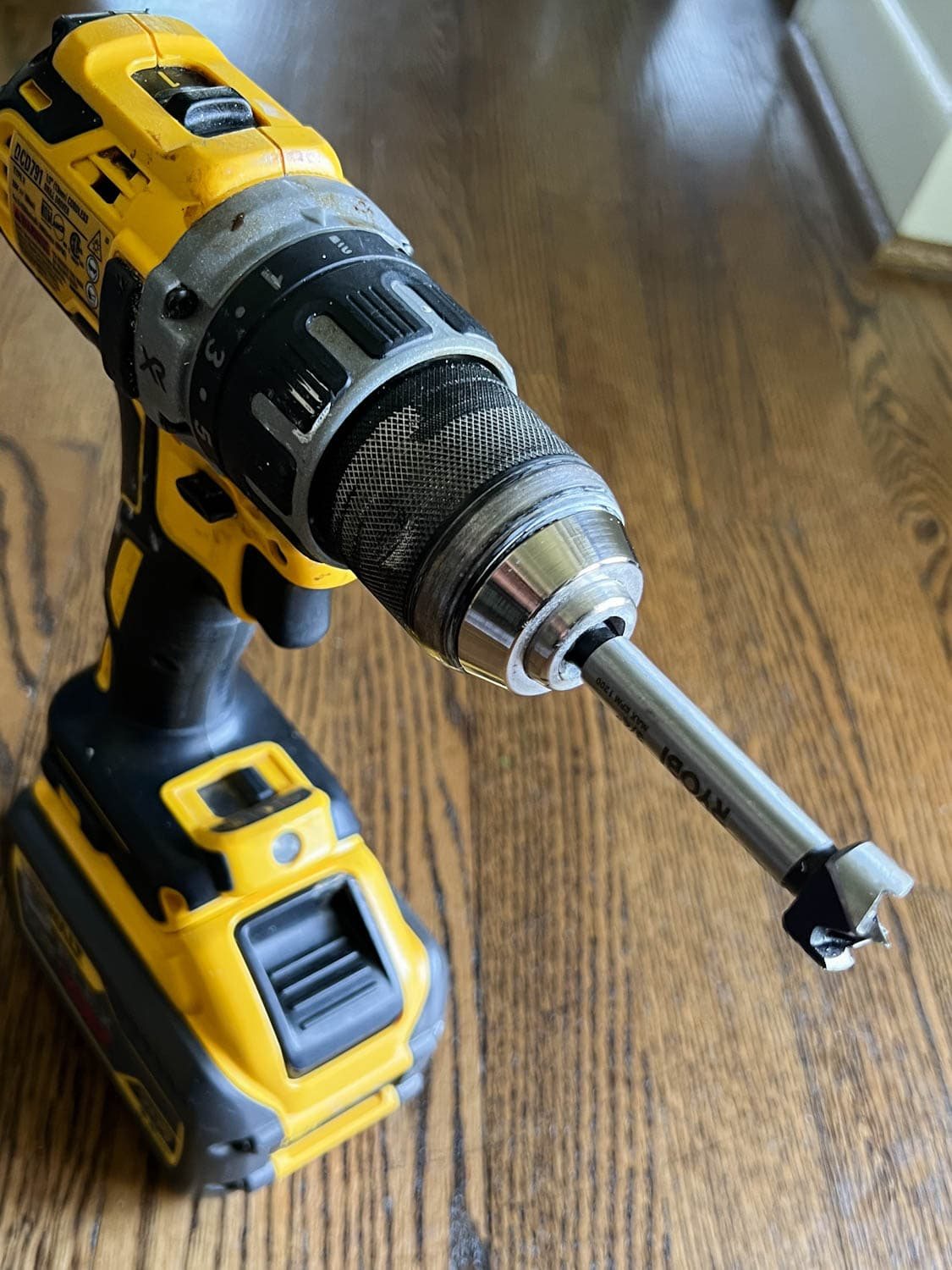 a forstner drill bit on a drill for removing old adhesive in stair treads