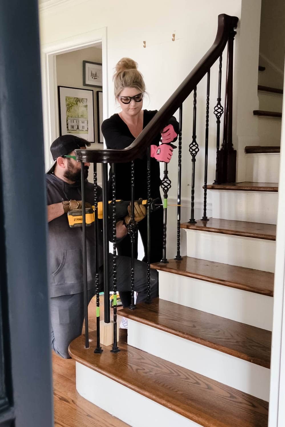 couple working together to remove old stair spindles from railing