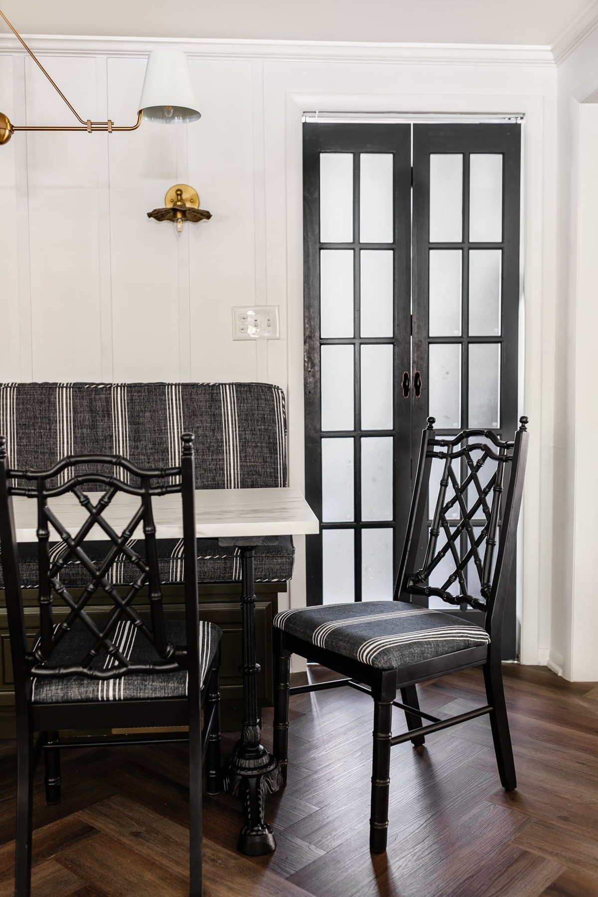black bamboo chairs with striped upholstered seats in a breakfast nook with olive green banquette bench