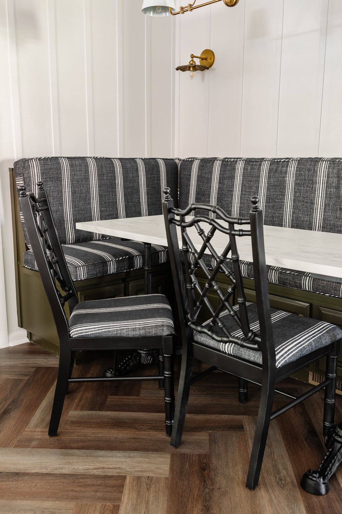 black bamboo chairs with striped upholstered seats in a breakfast nook with olive green banquette bench