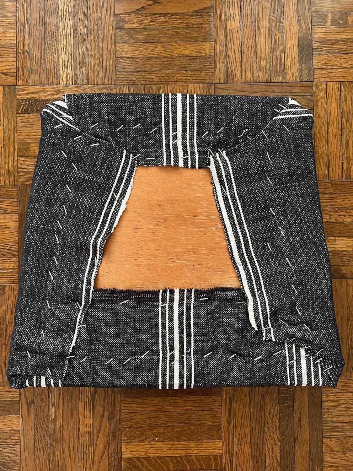 underside of recovering a dining chair seat with upholstery fabric and a staple gun