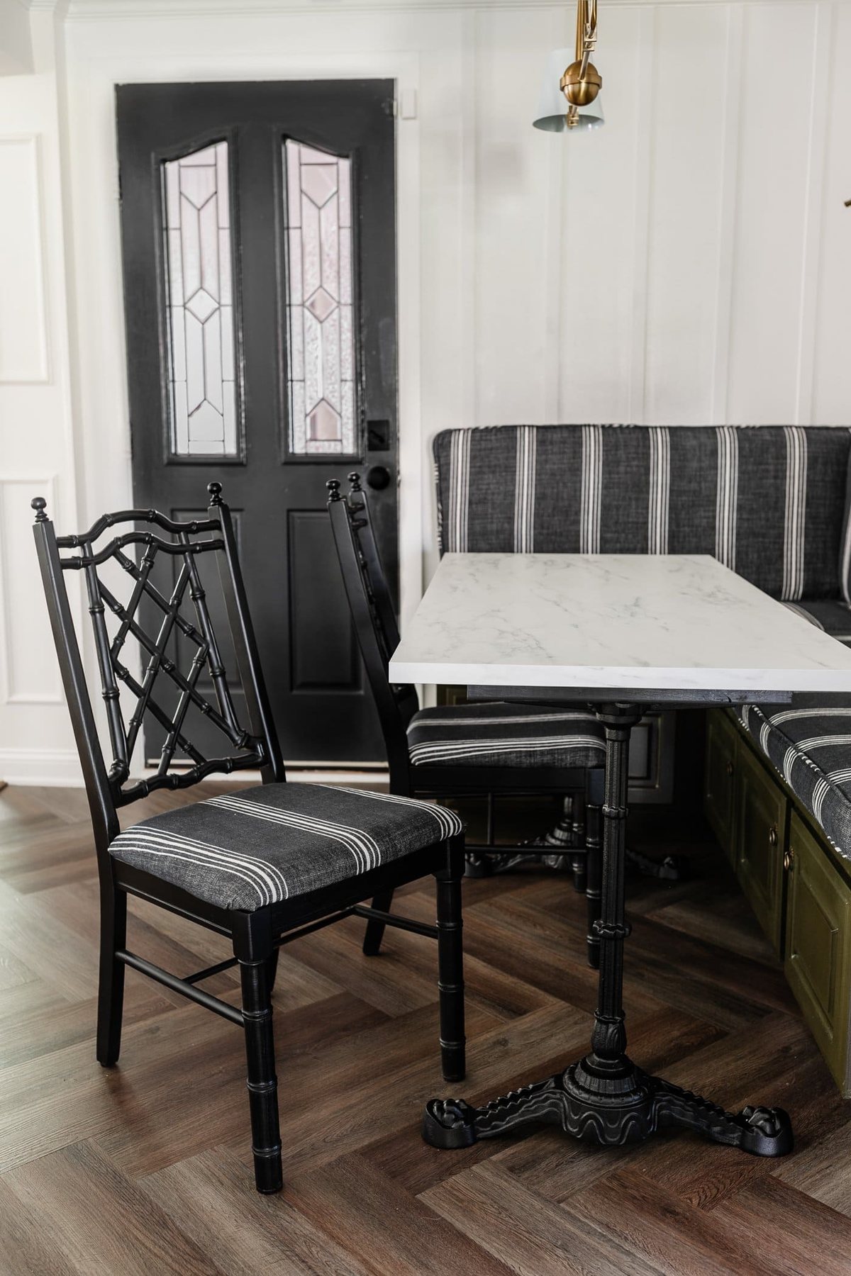 black bamboo chairs with striped upholstered seats in a breakfast nook with olive green banquette bench
