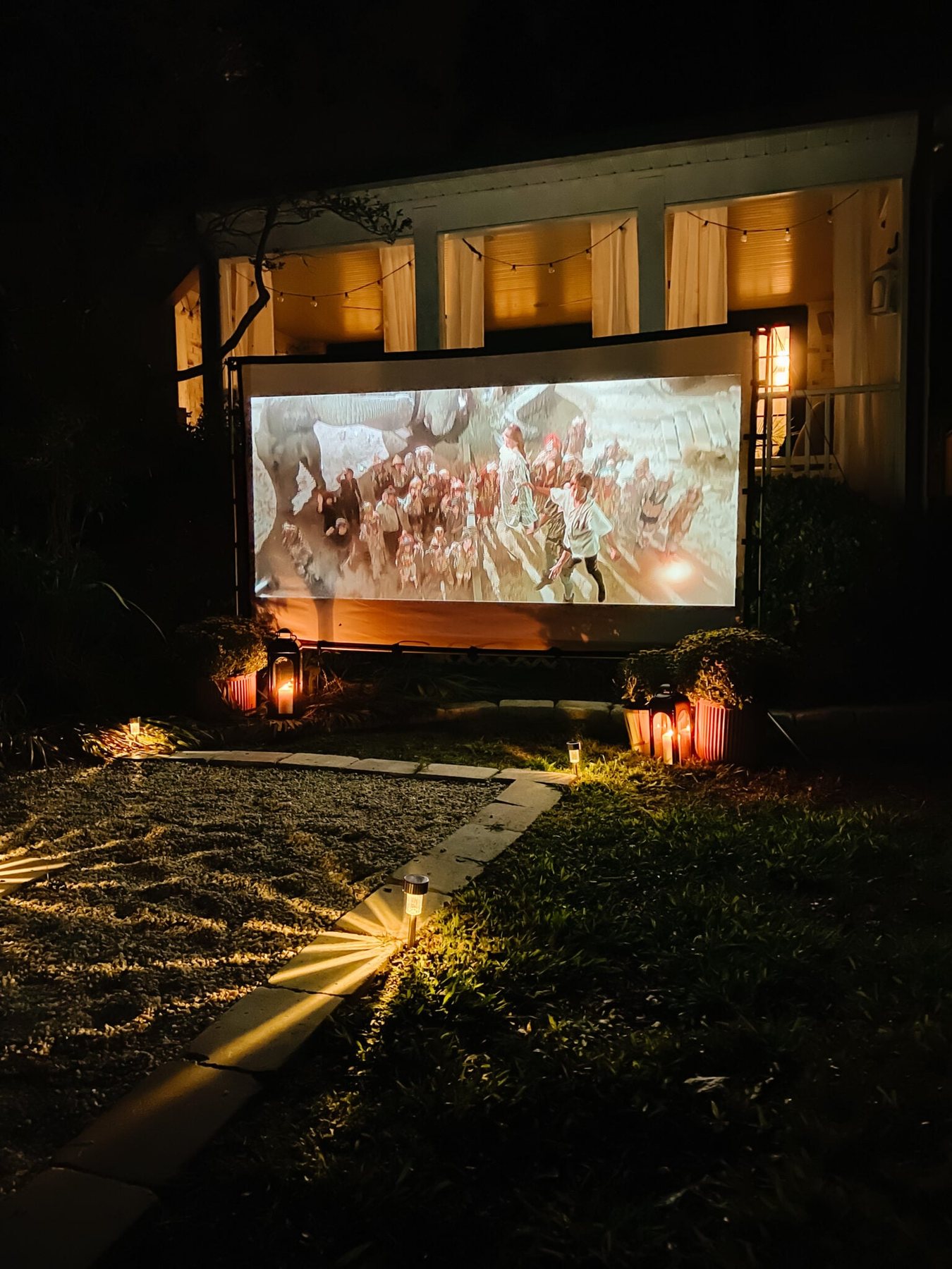 an outdoor projector and movie screen setup in a backyard for a DIY outdoor cinema