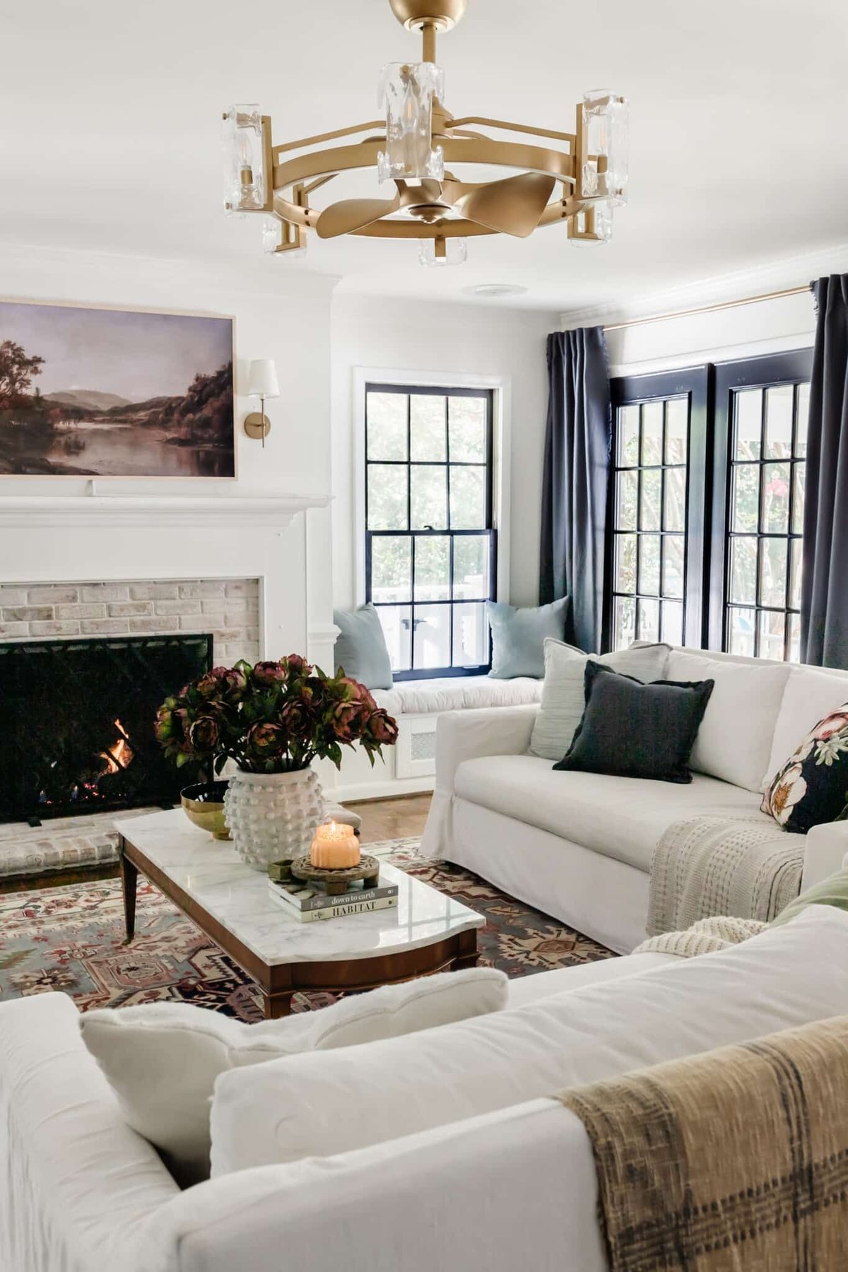 fall living room with blue curtains, vintage rug, and fall art on tv above fireplace