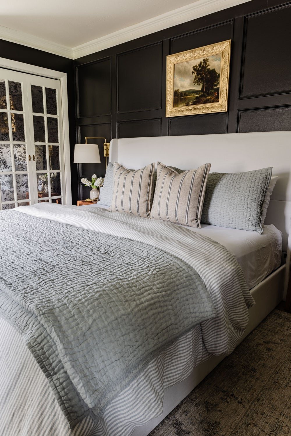 black primary bedroom white bed and mirrored bifold doors