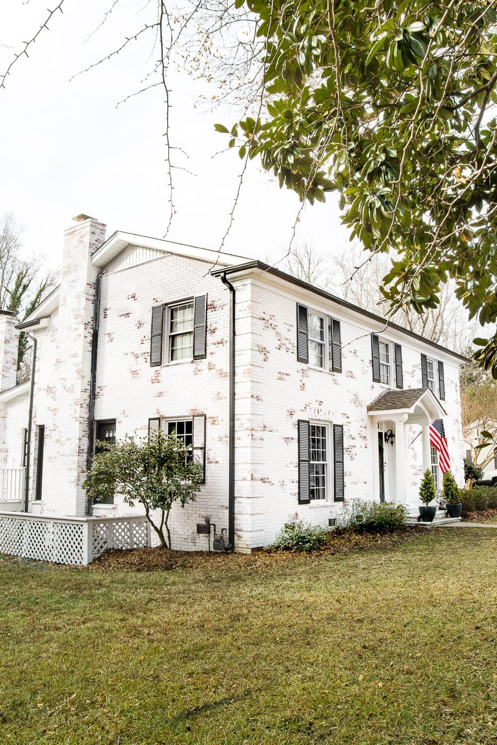 White brick colonial house with black shutters