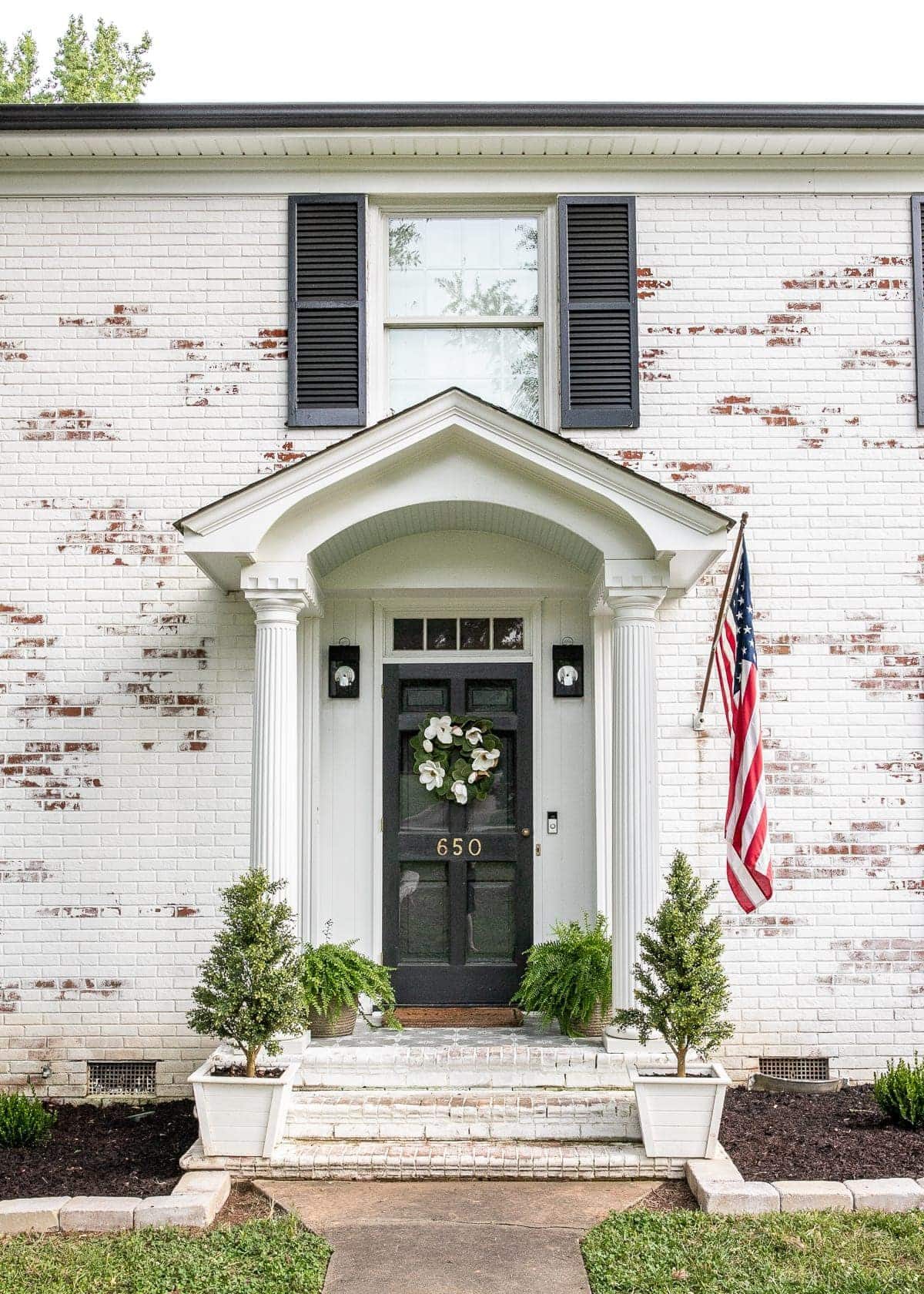 stenciled front porch with stone outlined flower beds