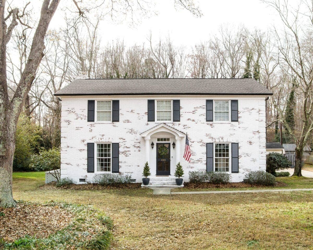 Romabio Bianco White limewash brick with Behr Cracked Pepper shutters and gutters and Behr Ultra Pure White trim