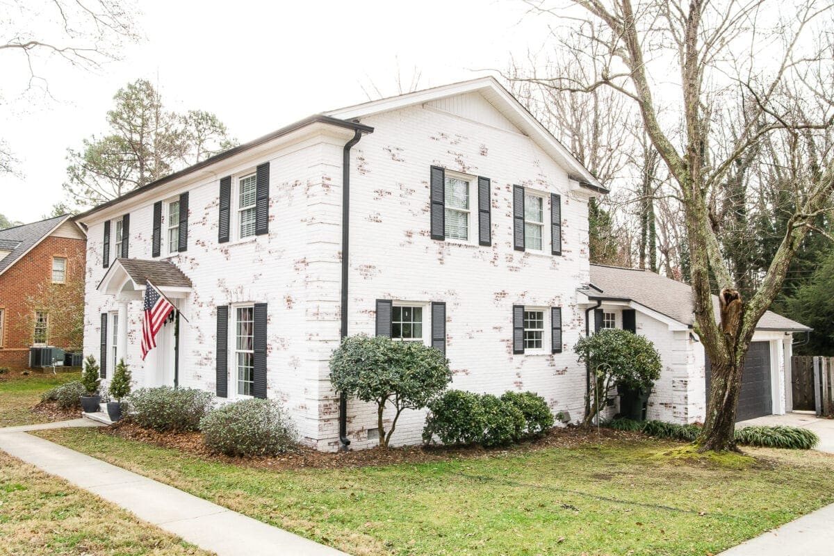 limewashed brick exterior makeover after with black shutters and gutters
