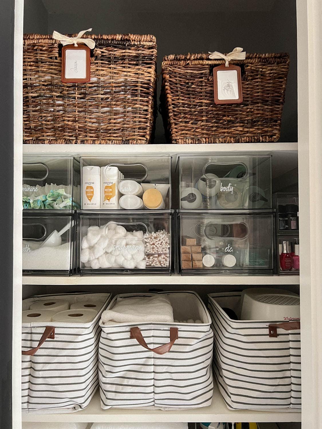 pair of baskets storing bedsheets and clear bins storing soaps and toiletries