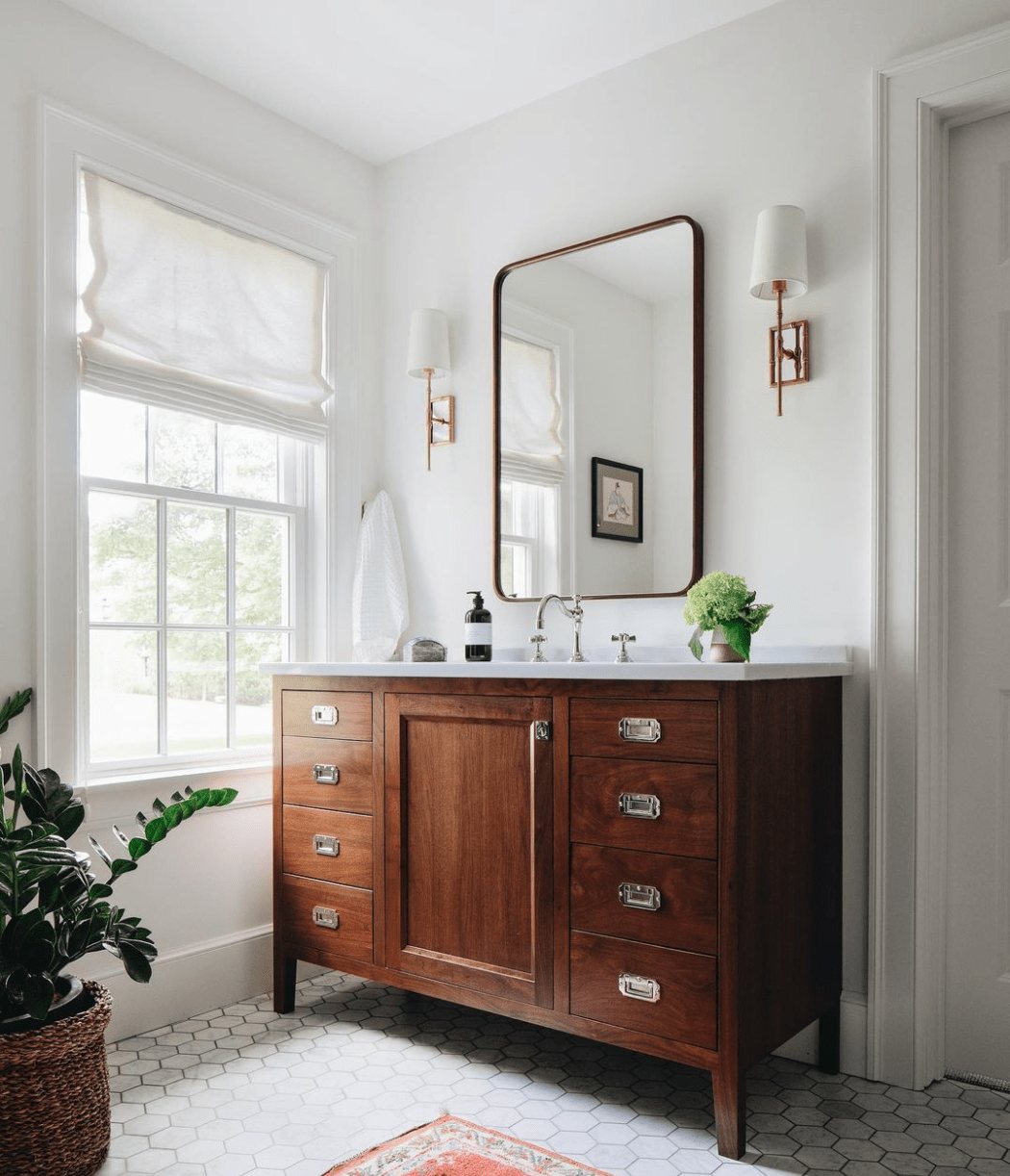 medium toned wood bathroom vanity with hexagon tile and shaded sconces