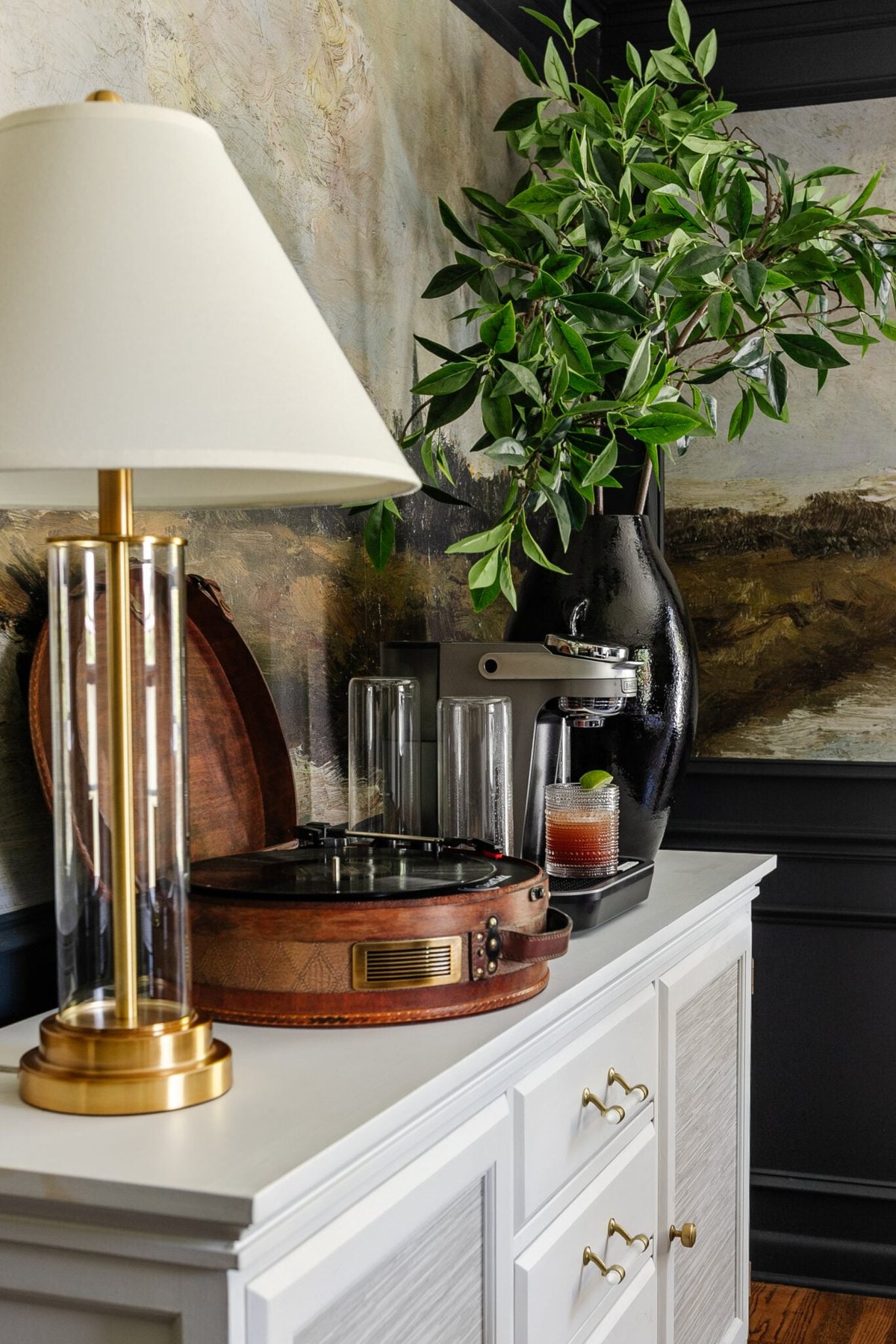 drink machine on a dining room buffet sideboard with lamp, record player, and vase of branches