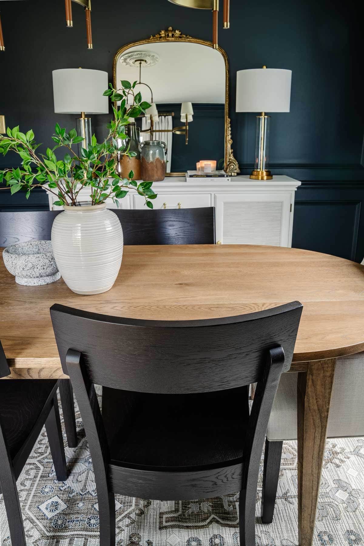 classic modern dining room with midcentury modern table, black chairs, and French mirror