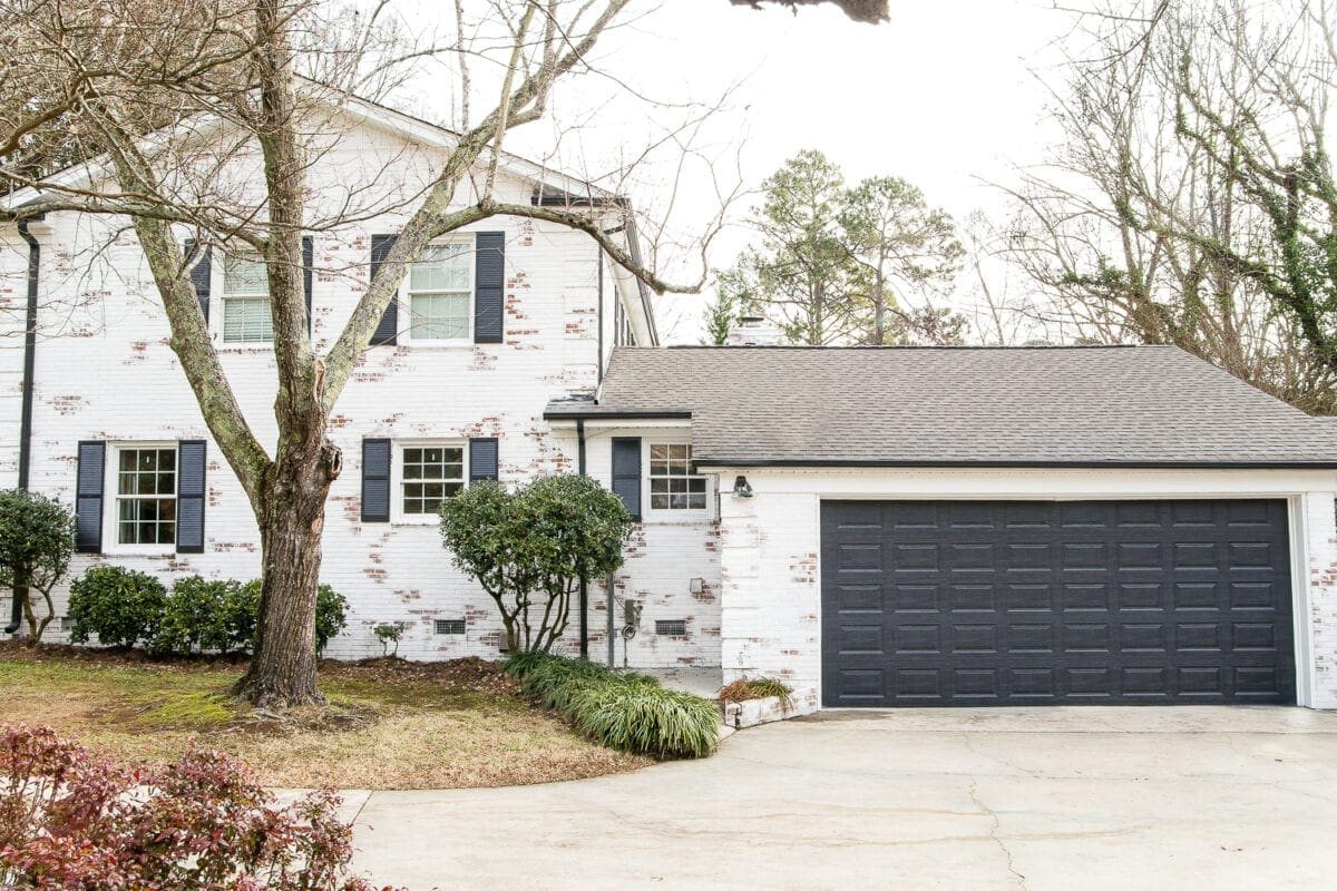 limewashed brick house makeover with black garage door and black gutters and shutters