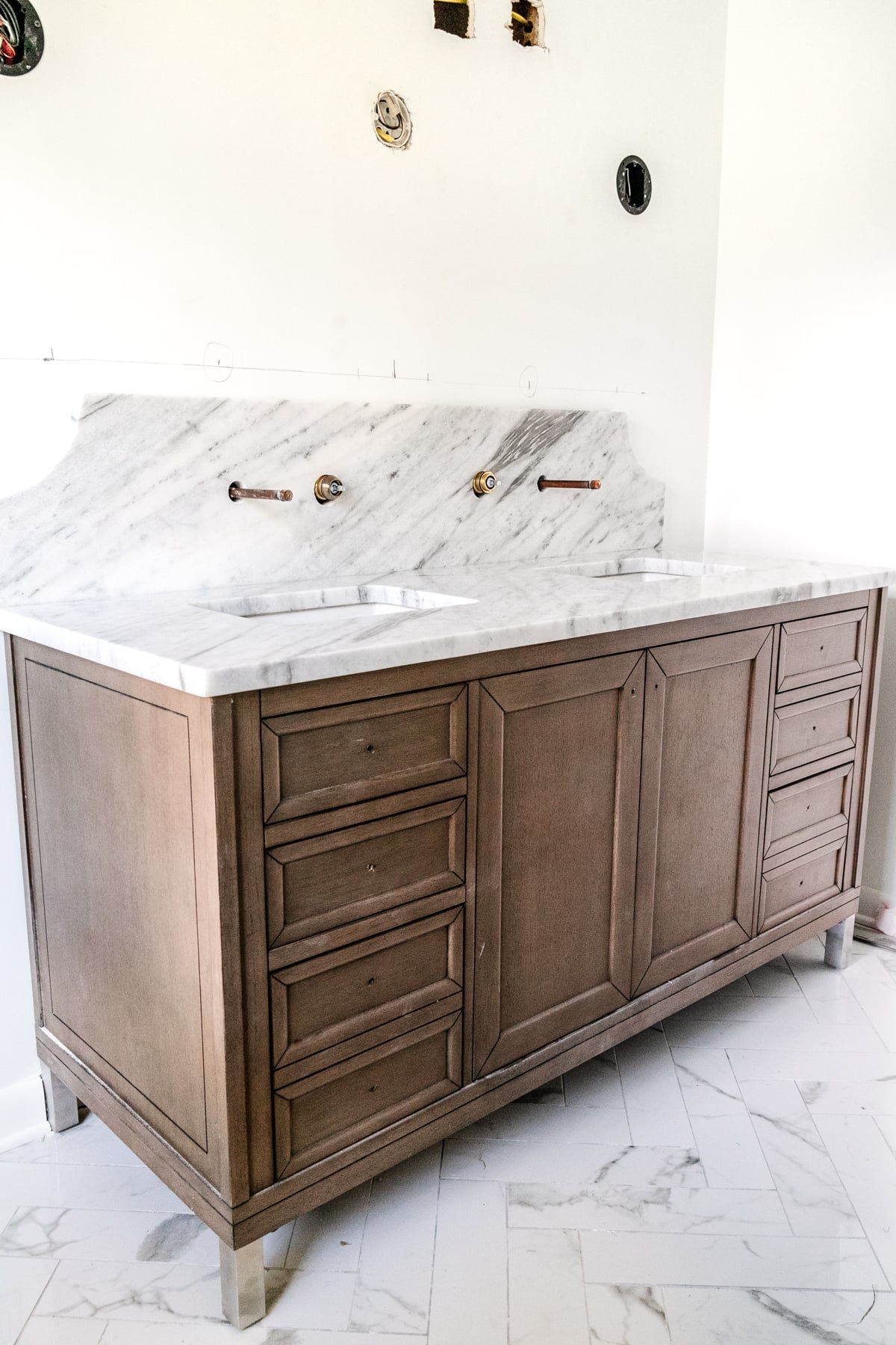 wood vanity with scalloped marble backsplash and herringbone tile