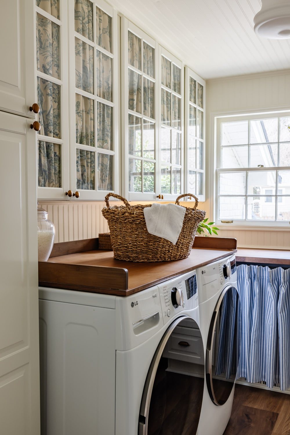 small laundry room organization with gathered fabric glass front cabinet doors