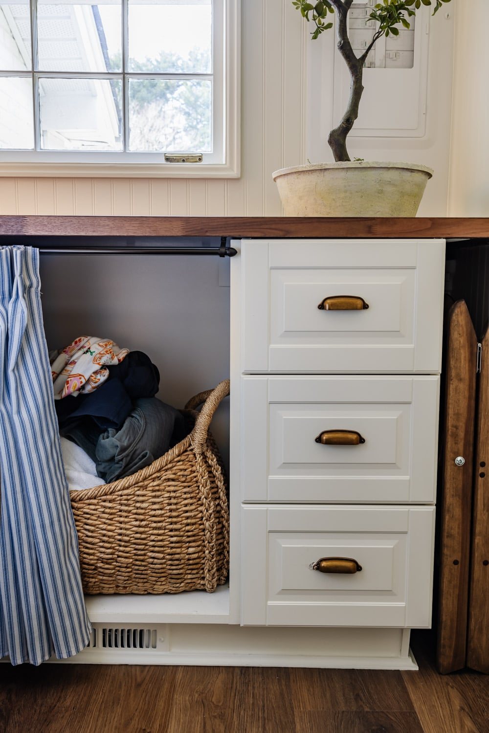 small laundry room organization - hamper basket covered by under countertop skirt