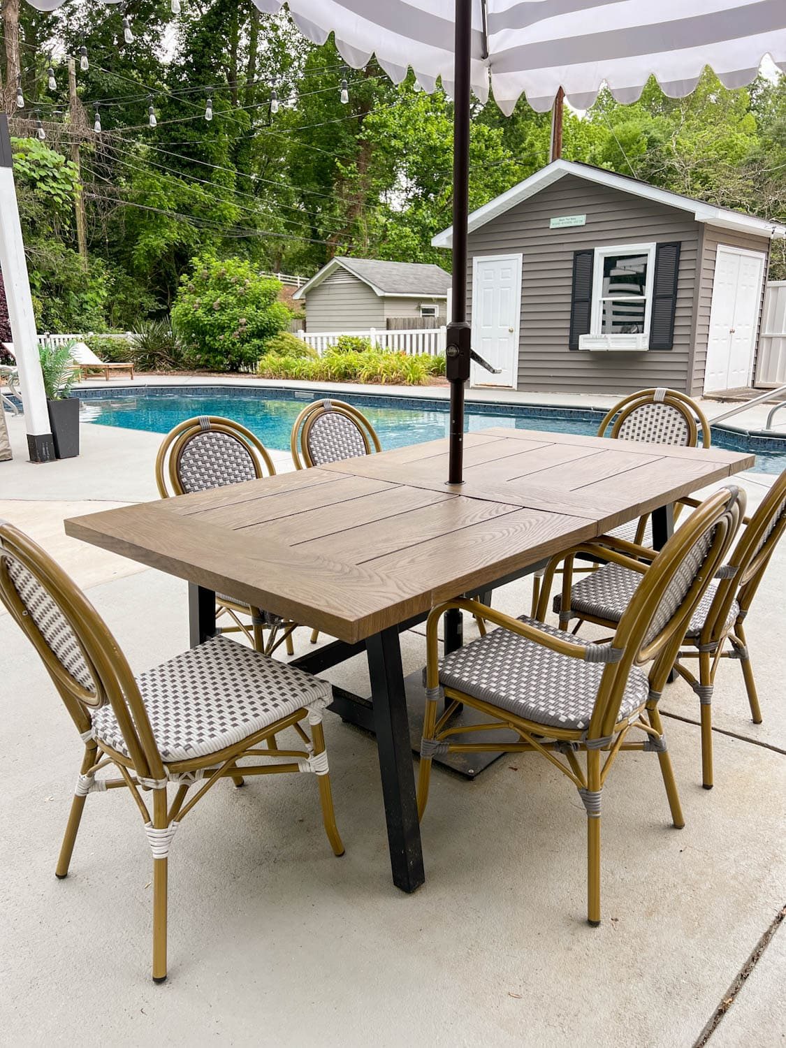 outdoor table beside a pool in a backyard with french bistro chairs