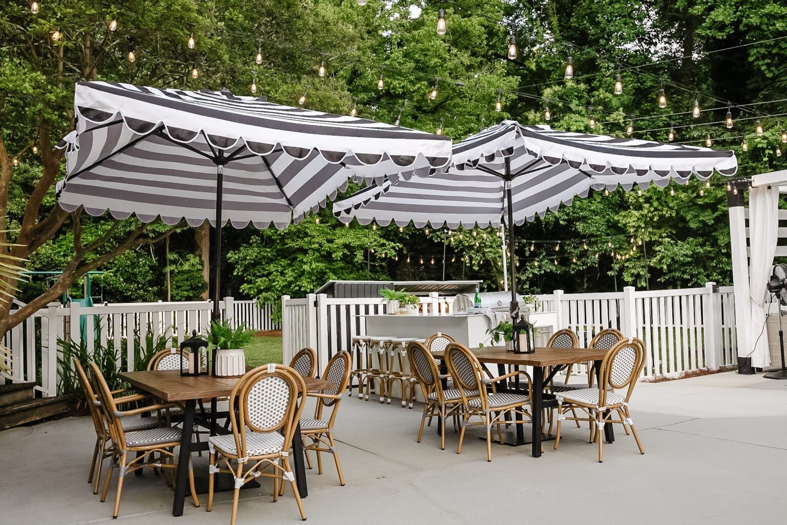 backyard patio dining sets with striped umbrellas beside an outdoor kitchen