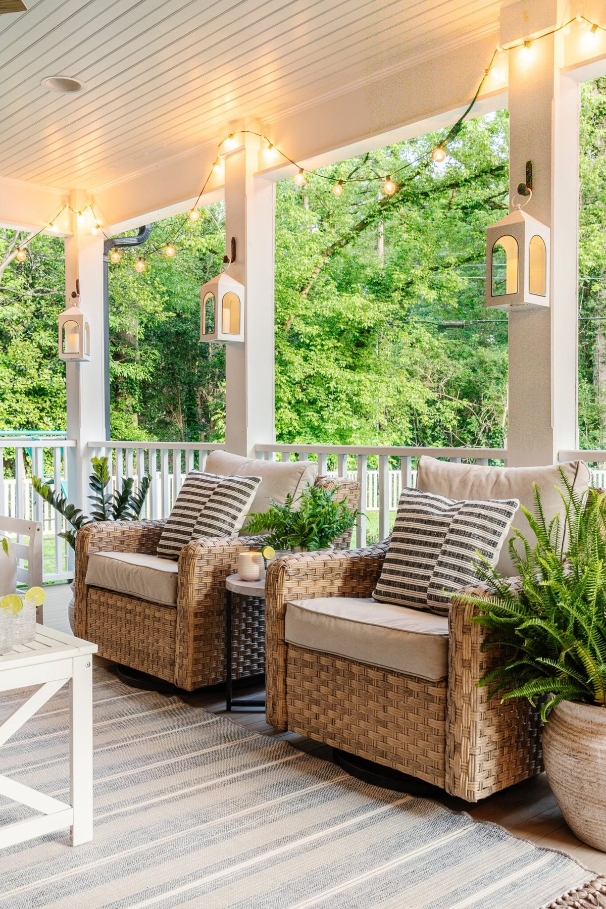 outdoor swivel chairs on a back porch with white coffee table and striped outdoor rug