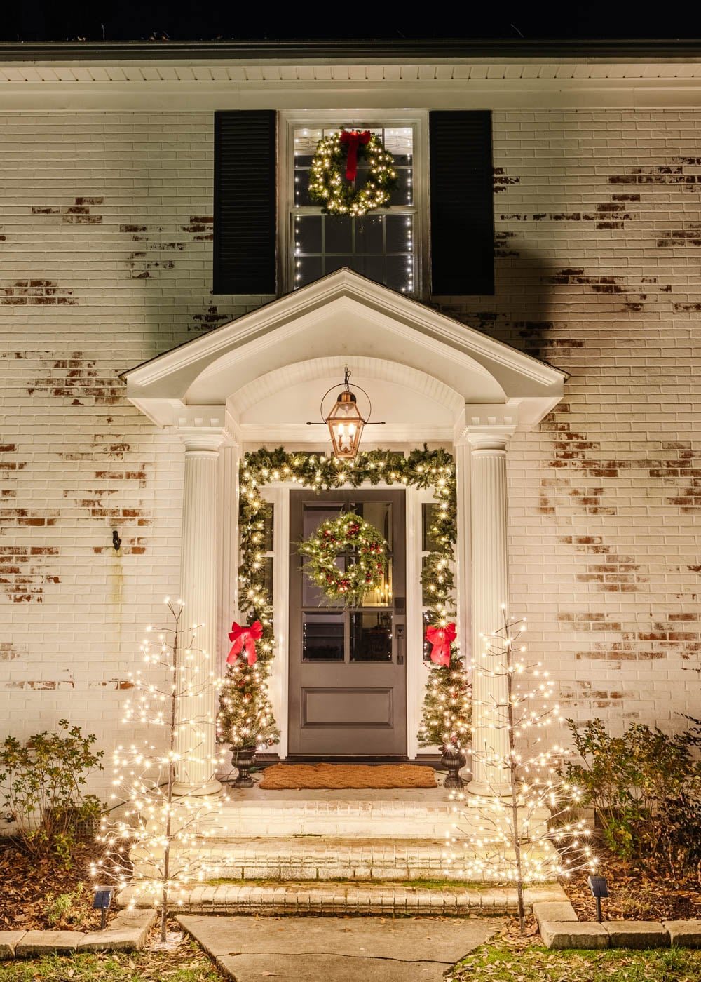 porch stoop Christmas decor with garland trees and twinkle lights