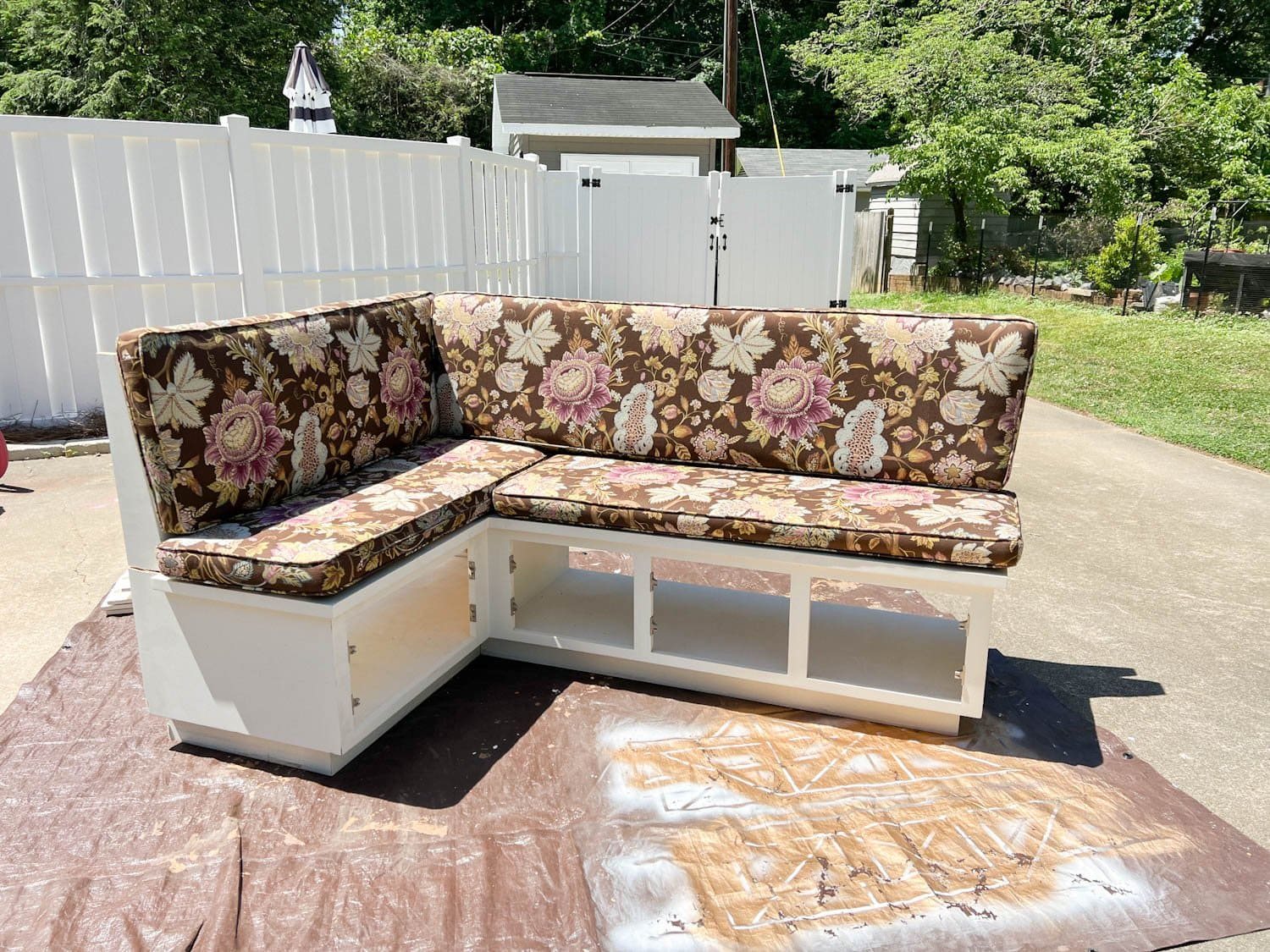 white thrifted banquette bench before with floral upholstered cushions