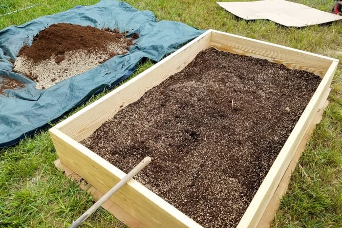 mixing soil, peat moss, vermiculite, and compost together for building a raised bed vegetable garden frame