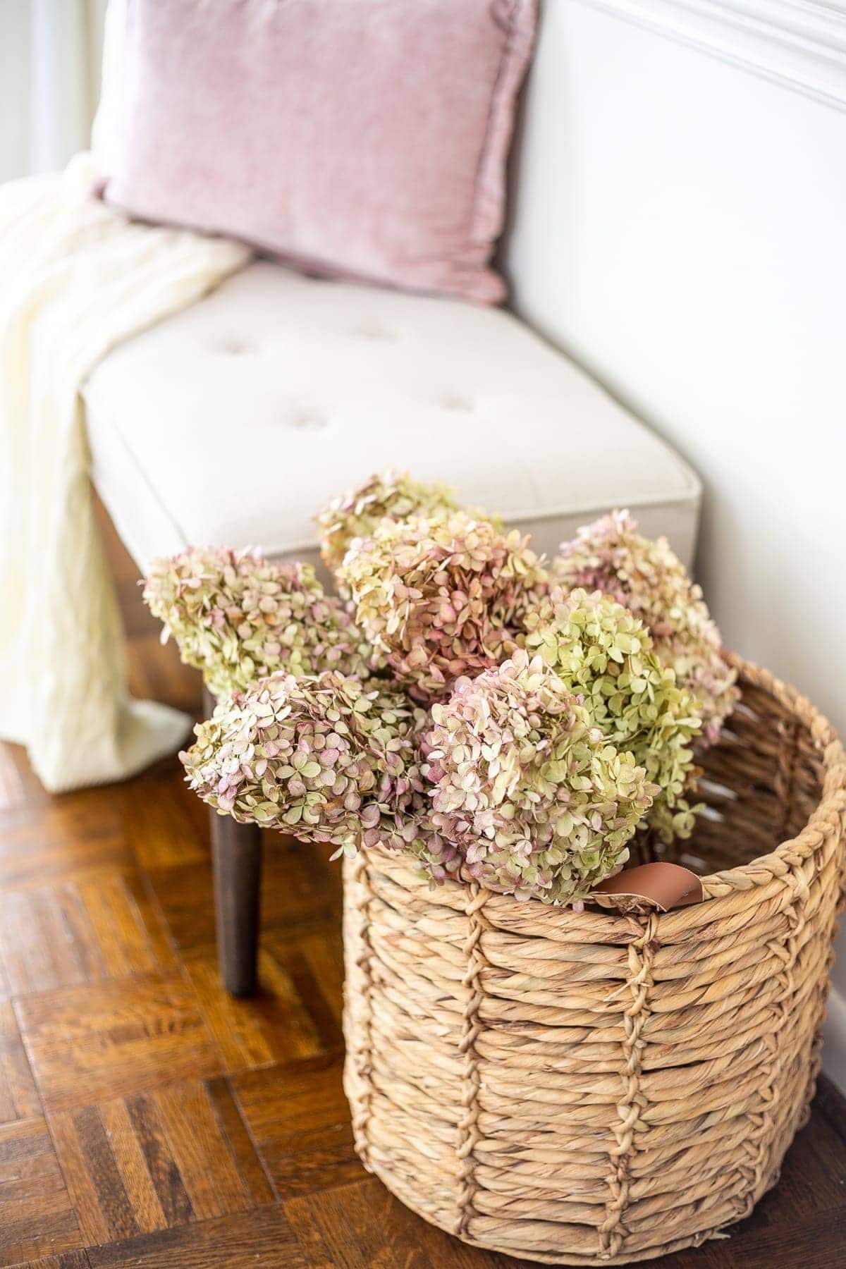 dried hydrangeas in a basket next to an entryway bench