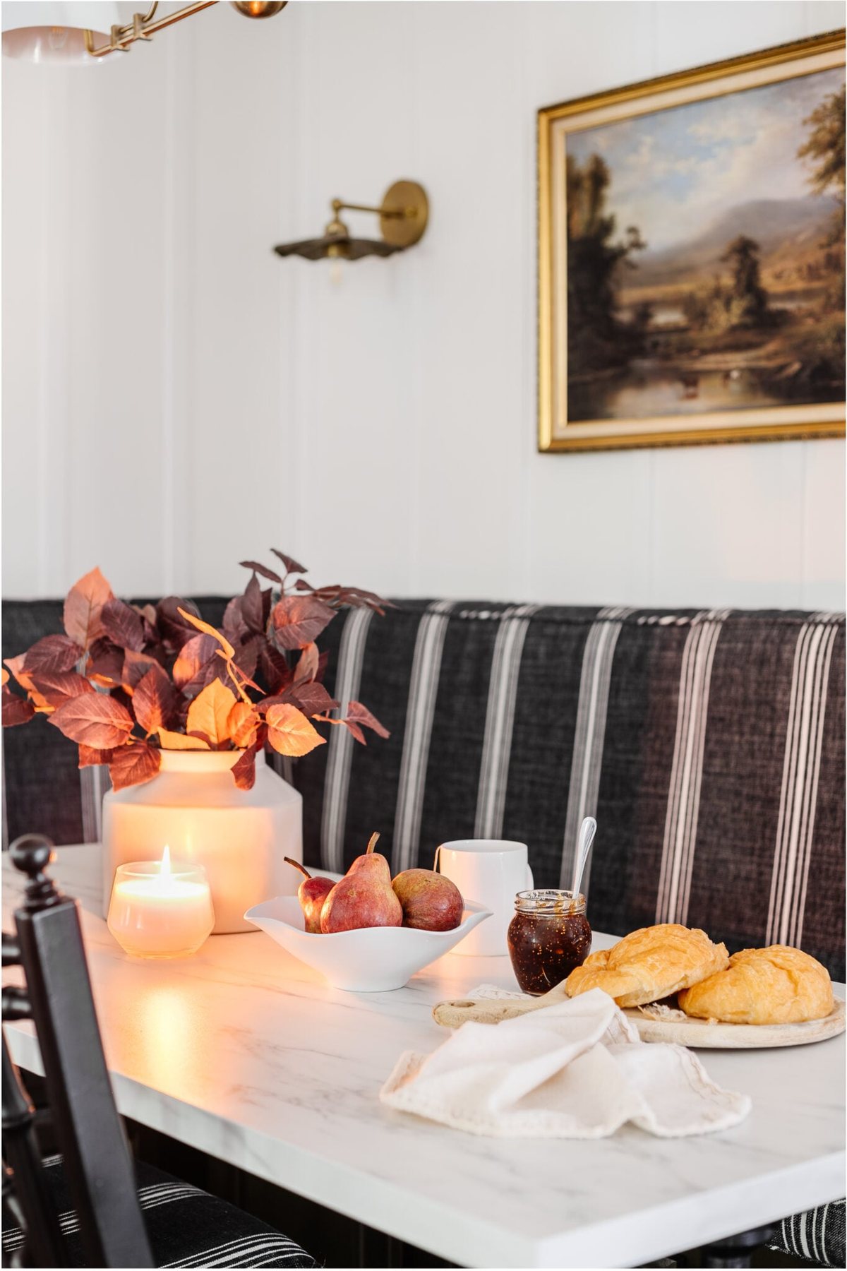 scalloped fruit bowl of pears on a dining room table decorated for fall