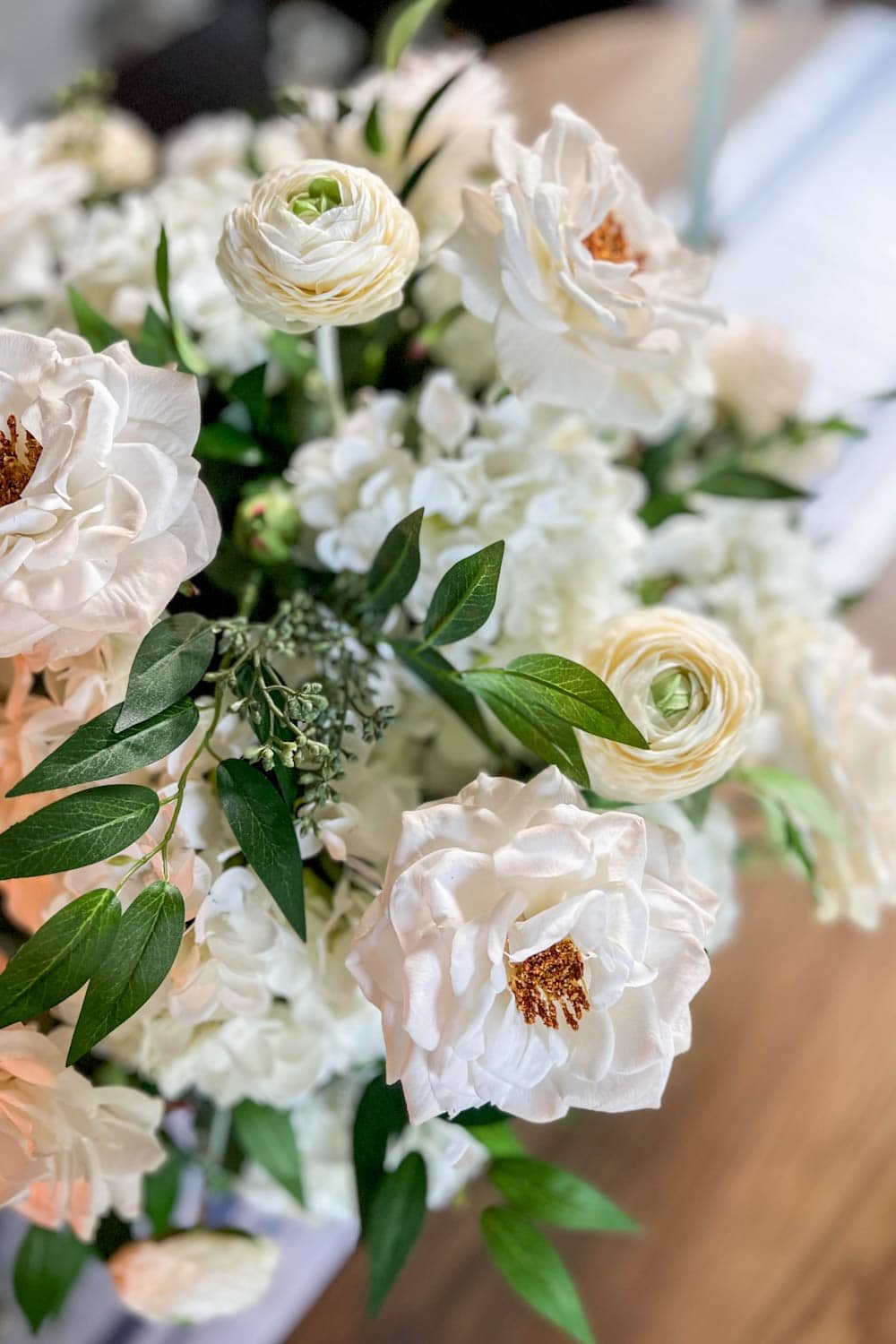 fake flower arrangement centerpiece using faux hydrangeas, roses, ranunculus, ruscus, and eucalyptus