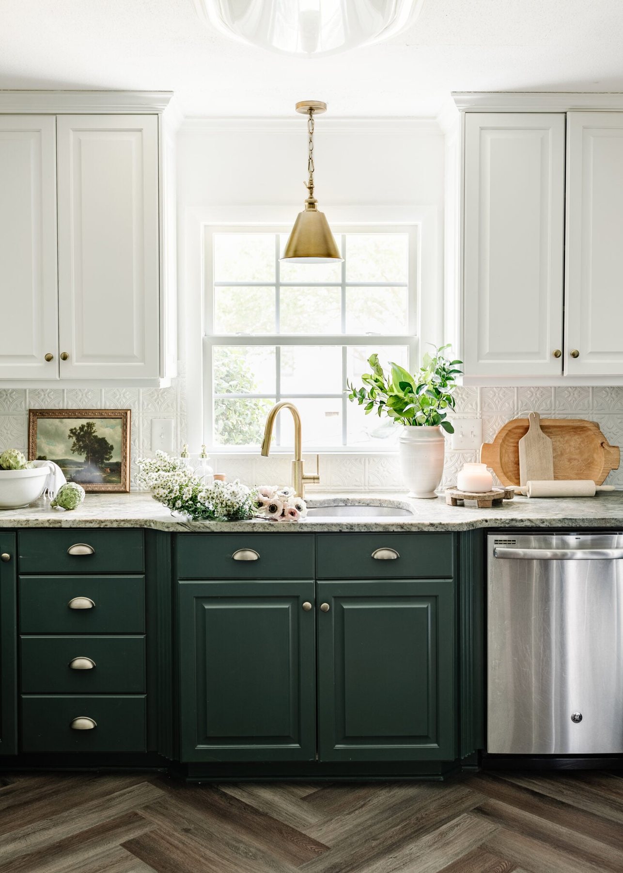 kitchen sink in front of window with green and white cabinets