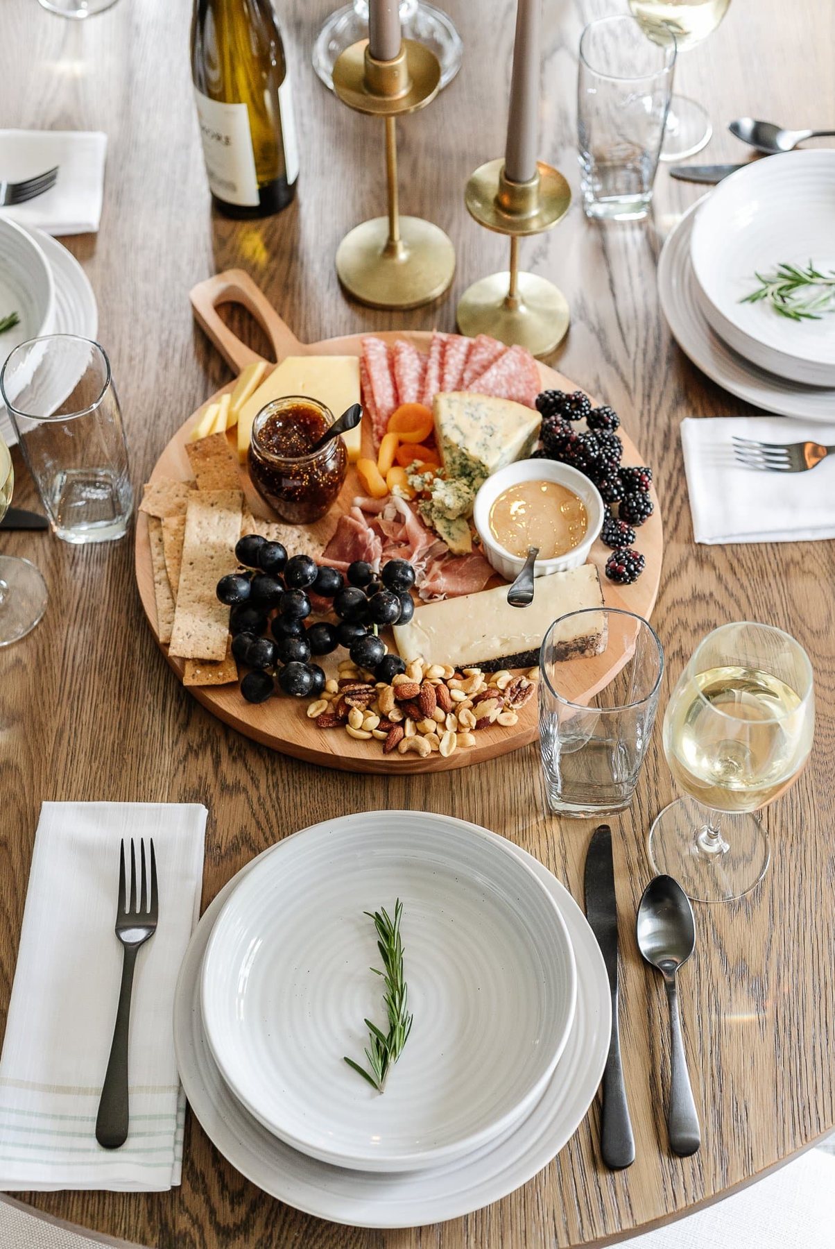 charcuterie board and simple place setting with a rosemary sprig