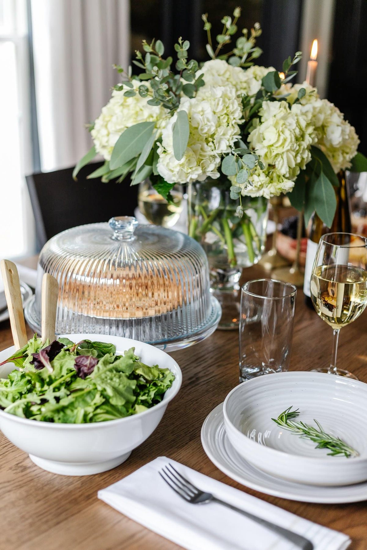 dinner table serving dishes - cake dome, salad bowl, vase of flowers